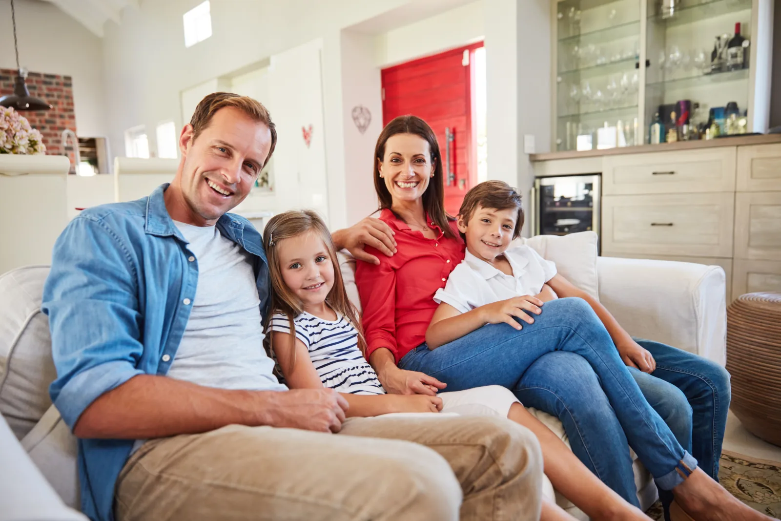 Deux parents et leurs deux enfants réunis sur le canapé de leur salon.