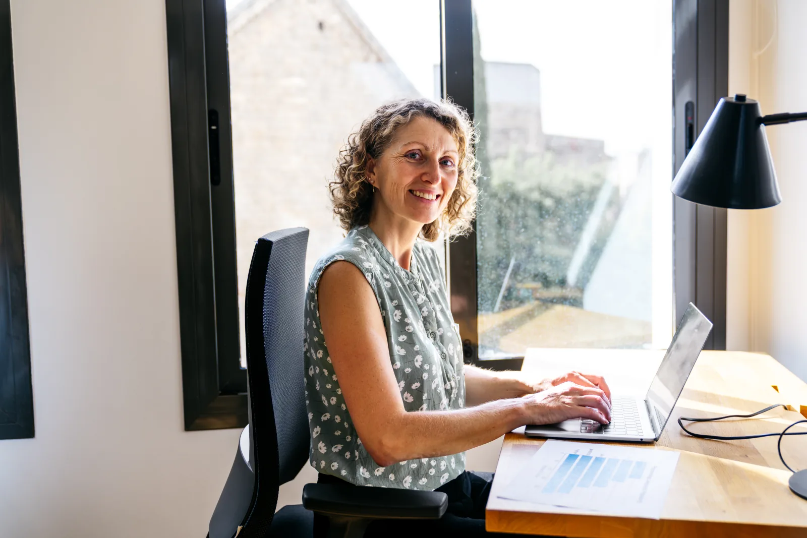 Une professionnelle travaille sur son ordinateur portable dans un bureau lumineux.