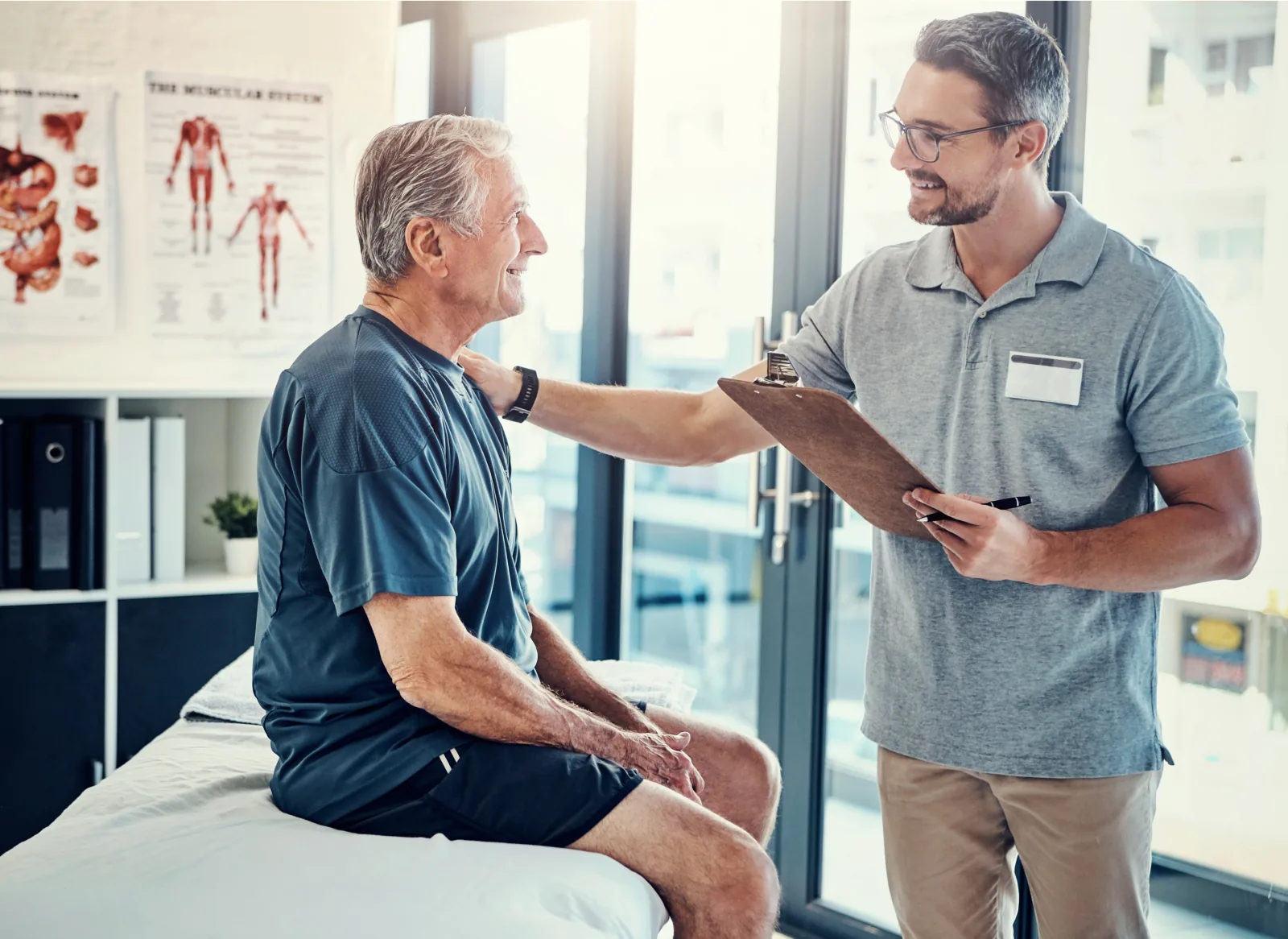 Un kinésithérapeute échange avec un patient dans son cabinet.